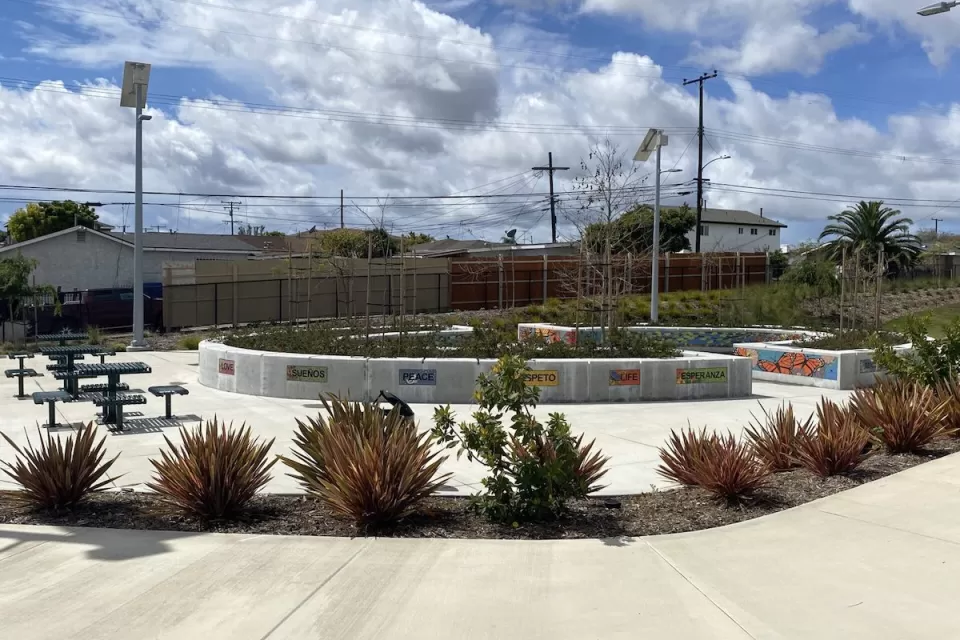 Concrete walkway with landscaping, decorative tiles, and picnic tables in a Los Angeles County park.